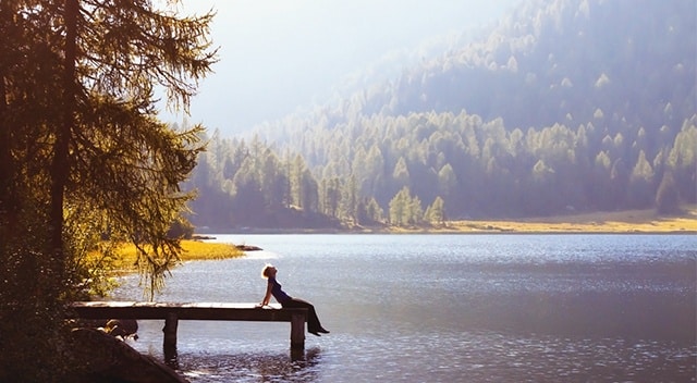 Person sitting on end of dock on lake